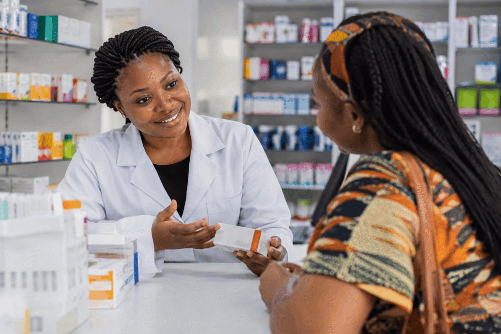 Why Are My Inner Thighs Dark? What Is Really Going On 4 A smiling pharmacist in a white coat hands a customer a medication box for treating skin discoloration at the pharmacy counter.